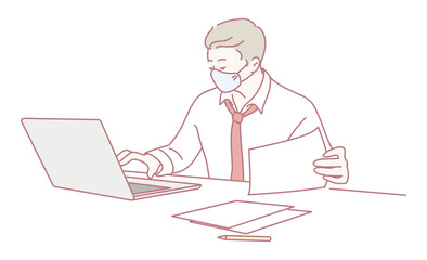 A focused man in a mask works on his laptop while handling important documents, showing remote work
