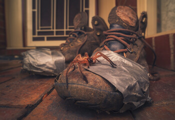 Close-up of a Huntsman spider on an old worn out pair of walking boots held together with masking tape outside a front door