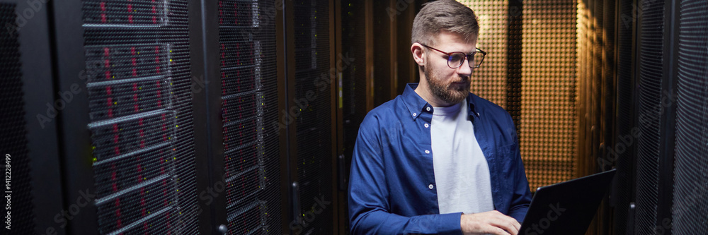 Poster website header shot of male it professional working in server room with focus on network maintenance