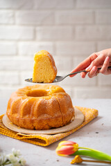 Egg liquor cake for Easter holidays. Bundt cake on a light background with tulip flowers. Easter festive food. Eierlikörkuchen in German cuisine. Food photography. Woman serving a cake