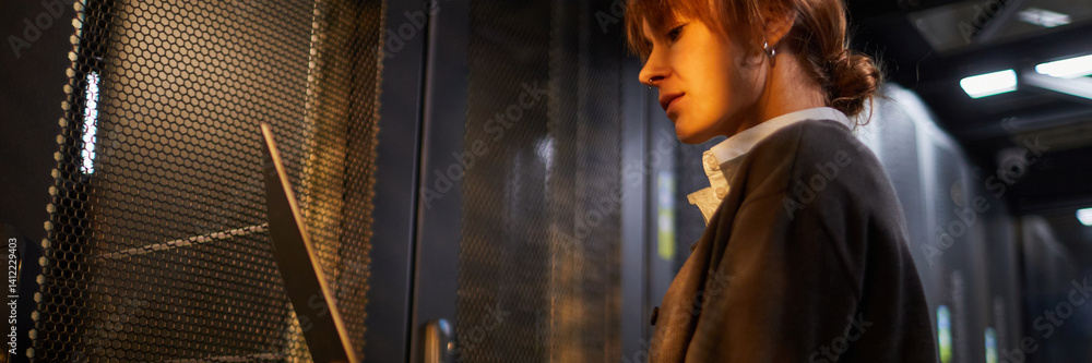 Poster website header shot of female engineer accessing server racks in data center, focusing on maintenanc