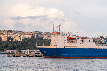 Colorful cargo ship docked by the Bosphorus with city skyline and cloudy sky in the background...