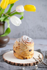 Easter Bread or Kulich with raisins. Easter yeast twisted cake Cruffin, painted eggs and tulip flowers on a stone background. Easter food.