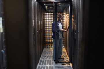 Technician performing routine maintenance in server room with various devices and gadgets around...