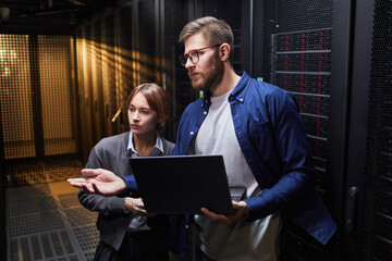IT professionals discussing server infrastructure details in a data center environment, featuring...