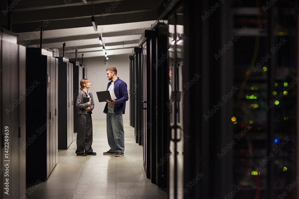 Aufkleber two individuals discussing work in a well-lit, contemporary data center while holding laptop. enviro