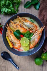 Thai style Tom Yum Kung Creamy river prawn spicy soup in black bowl on wooden background
