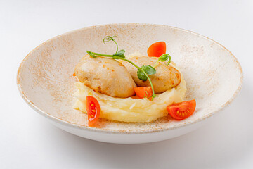 Delectable fish dumplings sit atop velvety mashed potatoes, garnished with vibrant cherry tomatoes