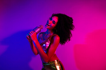 Vibrant young woman singing in neon lights with colorful glowing backdrop embodying energy, fashion