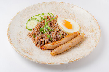 Delicious seasoned buckwheat with juicy sausages and a sunny-side-up egg, topped with cucumber