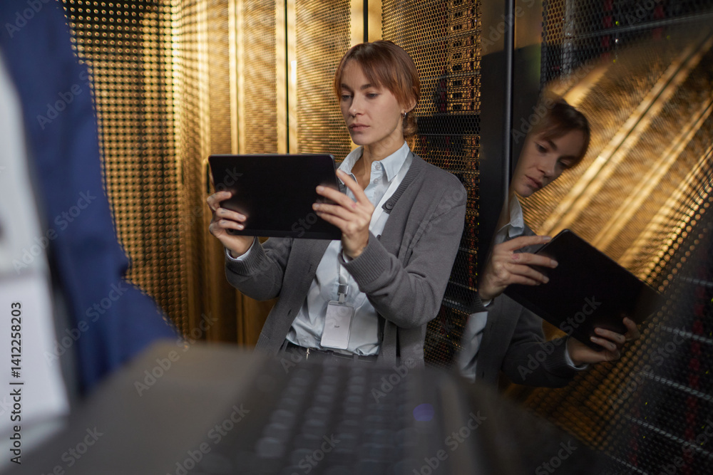 Poster technician holding tablet device in server room, monitoring systems with focused expression. server 