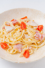 Creamy fettuccine twirled with savory meats and garnished with vibrant cherry tomatoes