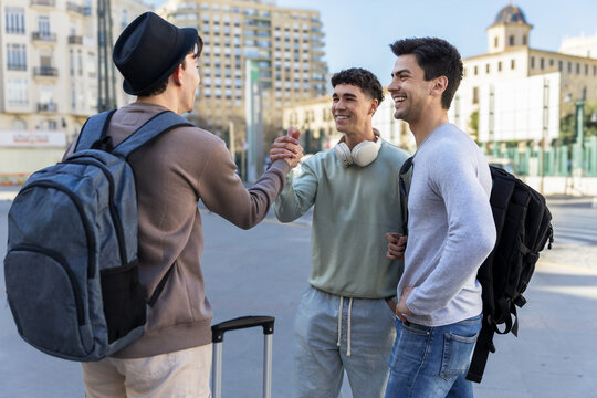 Two friends picking up a visiting buddy at the station with a warm welcome