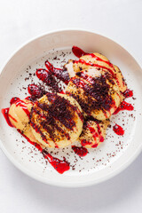 Delicious dessert featuring creamy textures with berry drizzle and cocoa on a pristine white plate