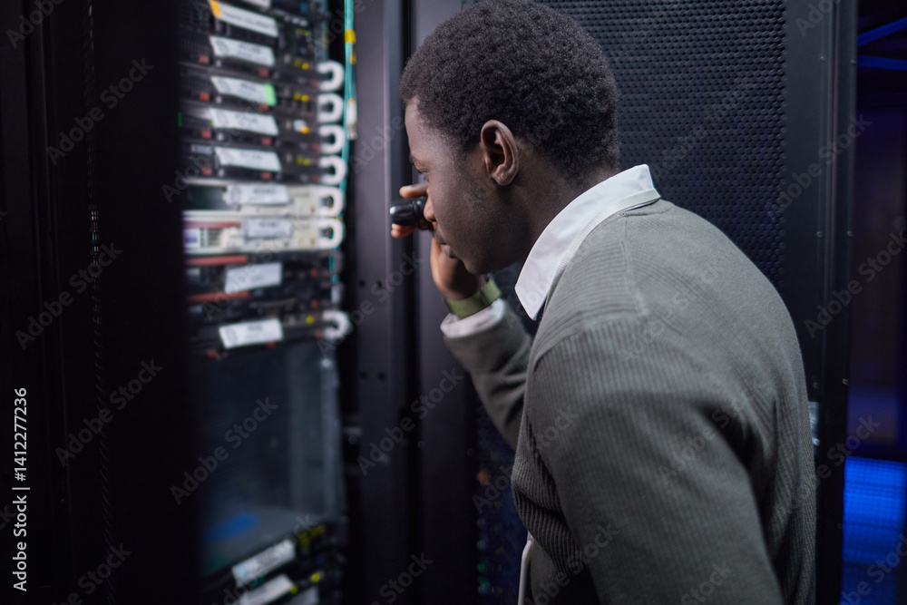 Poster african american man in formal attire inspecting server nodes in data center. he is holding tool, ex