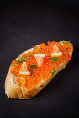 Savor the beauty of toasted bread generously adorned with bright orange caviar and citrus accents