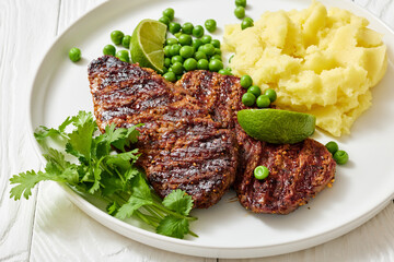 grilled beef cutlets with potato mash, green peas