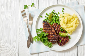 grilled beef cutlets with potato mash, green peas
