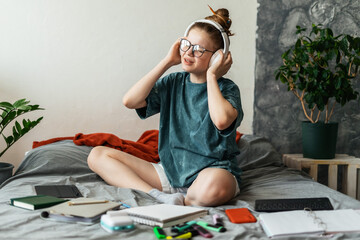 Young student happily enjoying music while engrossed in studying in cozy room environment