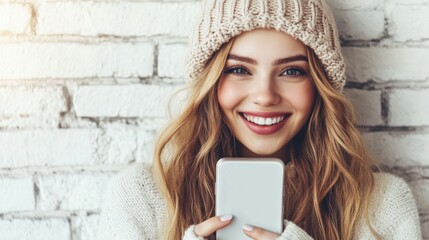 Portrait happy smiling young woman with phone in winter hat, white sweater, girl holding smartphone
