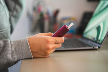 unknown woman work on laptop and use electronic cigarette at office