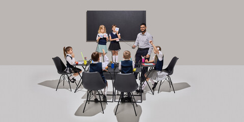 Creative English lesson with teacher and children using flashcards and pointer in classroom setup with bright materials. Concept of education, school, interactive learning, childhood development.