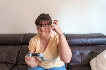 Frustrated woman playing video games clenching teeth and gesticulating on sofa