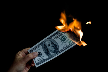 A hand holding a banknote is burning