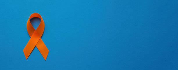 Skin cancer awareness month concept. Orange color ribbon on blue background. Symbolic for Multiple Sclerosis day, self harm awareness, leukemia and kidney cancer. Poster, banner with copy space.