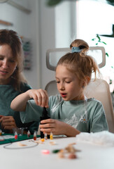 Fototapeta premium Crafting session features tools, UV resin, and various embellishments as mother guides daughter in creating custom trinkets. Artistic process strengthens their bond. Chemistry experiments at home