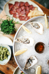 An overhead close-up of fresh oysters on ice, paired with lemon slices and sauces, styled in a rustic seafood restaurant with a soft, selective focus.