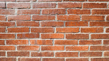 A close-up image of a textured brick wall with weathered red and brown bricks, showcasing natural details and imperfections.