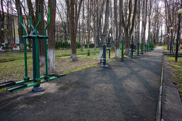 An outdoor gym with various exercise equipment installed in a public park setting.