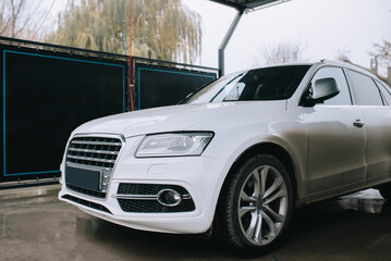 Dirty white car before washing at car wash station