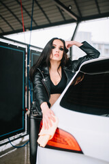 Sexy woman washing car in leather outfit