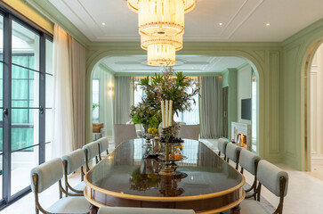 Beautiful luxurious traditional style dining room with bouquets of flowers on the table. Elegance dinning table with luxurious pendant.