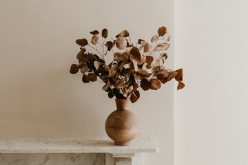 Dried Eucalyptus in Wooden Vase on Marble Mantel in Minimalist Interior