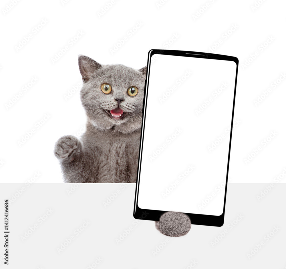 Fototapete surprised cat holding big smartphone with white blank screen and looking above blank banner. empty f