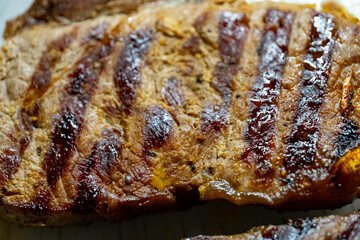 Close-up of grilled meat steak with charred grill marks and juicy texture. Macro shot of cooked beef surface. Barbecue food and protein meal concept