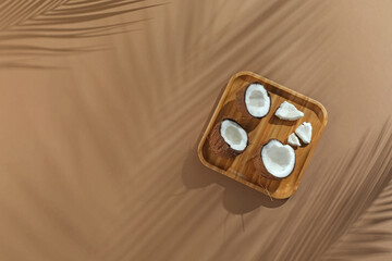 Fresh coconuts and shadow cast by tropical palm on beige background, top view. Space for text