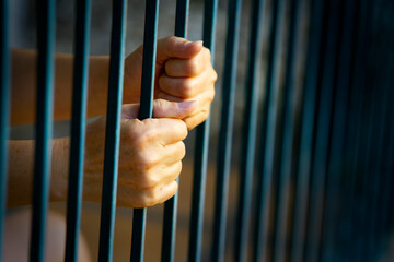 Hands Gripping Metal Bars Symbolizing Confinement and Despair