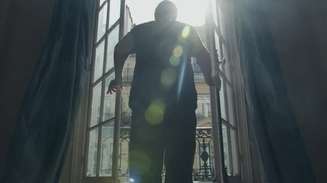 Man opening french window in paris apartment, welcoming new day