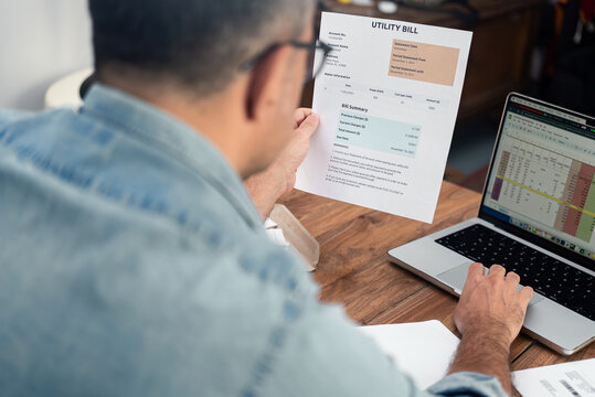 Mature man inputs utility bill data in digital spreadsheet working on computer, old male entrepreneur processes household expense count, regular payments organization