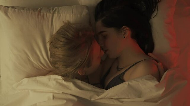 Top view young loving couple romantic time in bedroom. Man and woman half naked sensual lovers laying in bed together, passion, intimacy kissing, foreplay and bonding.