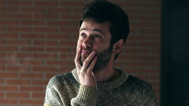 young man appearing perplexed and deep in thought. His gaze drops slightly as he processes something difficult or uncertain.
