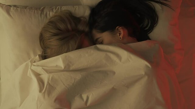 Top view loving couple romantic time in bedroom. Man and woman sensual lovers laying in bed together cuddle under sheet, passion intimacy foreplay and bonding.