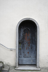 Old wooden door with weathered paint and stone arch in a quaint building located in a serene urban environment