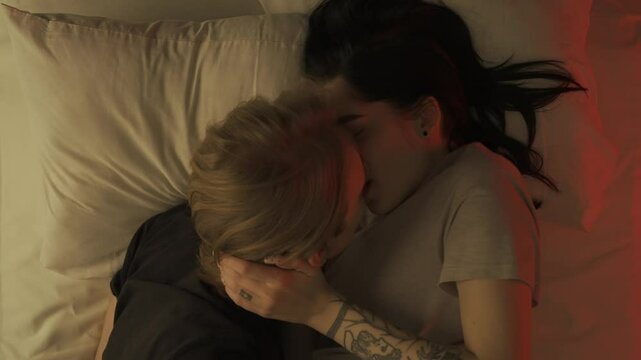 Top view young loving couple romantic time in bedroom. Man and woman half naked sensual lovers laying in bed together, passion, intimacy kissing, foreplay and bonding.
