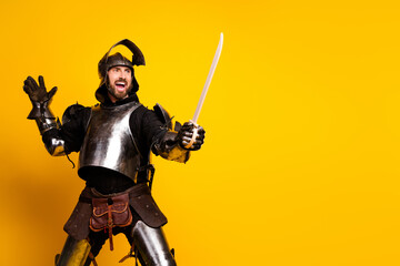 Naklejka premium Young man posing as a medieval knight against a vibrant yellow backdrop