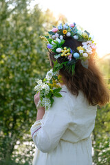 girl in white dress, decorative spring wreath crown with flower bouquet outdoor, nature background....